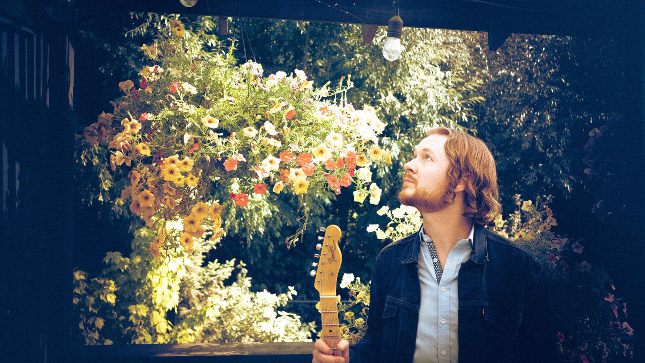Jon Martin and Lovers standing in front of a plant with flowers on it.